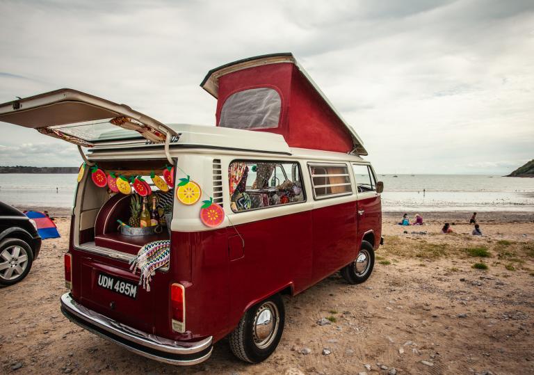 A VW campervan parked on a beach.