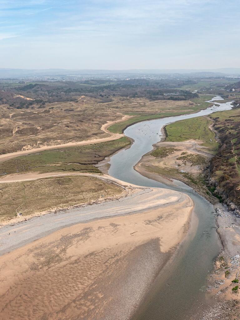 An aerial view of an estuary leading to a sandy beach.