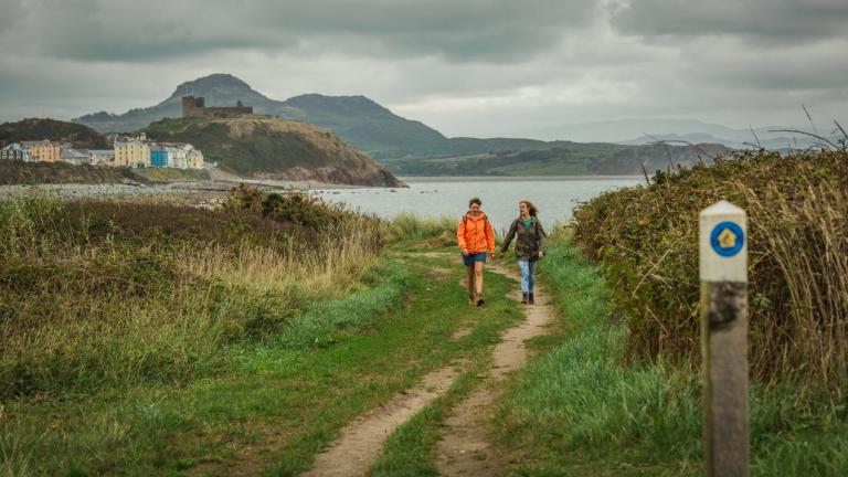 Zwei Frauen wandern auf dem Wales Coast Path in der Nähe von Criccieth.
