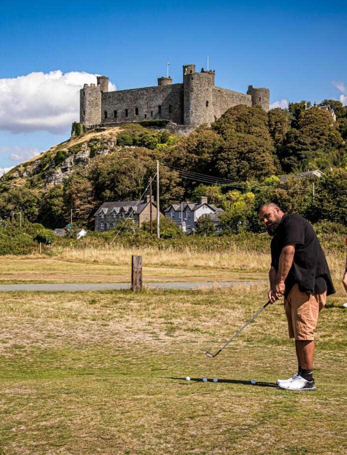 Two golfers on a golf course underneath a huge castle.
