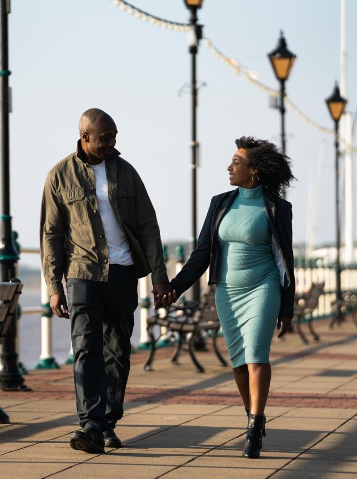 A man and a woman holding hands walking along a promenade.