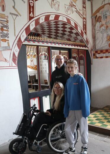 family including woman in beach wheelchair inside colourful church.