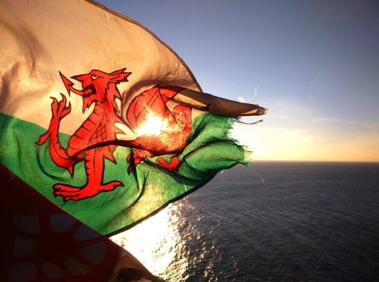 Welsh flag flickering against the sunset with the sea behind