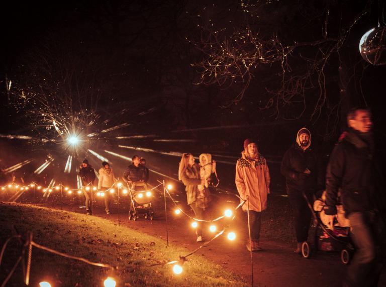 People walking the illuminated trail at Margam Country Park at Christmas time.