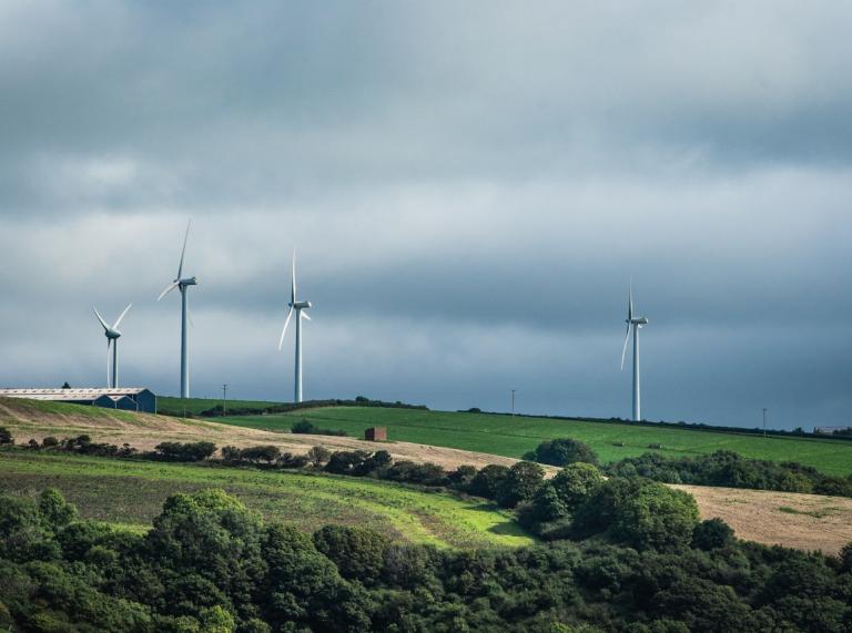 Wind turbines on a hill with a moody sky behind them.