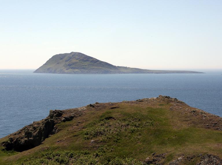 Blick vom Festland auf eine Insel mit Berg im Meer.