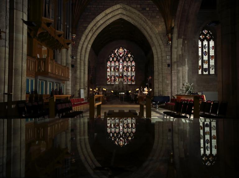 interior of cathedral with arched stain glassed window reflected in the floor.