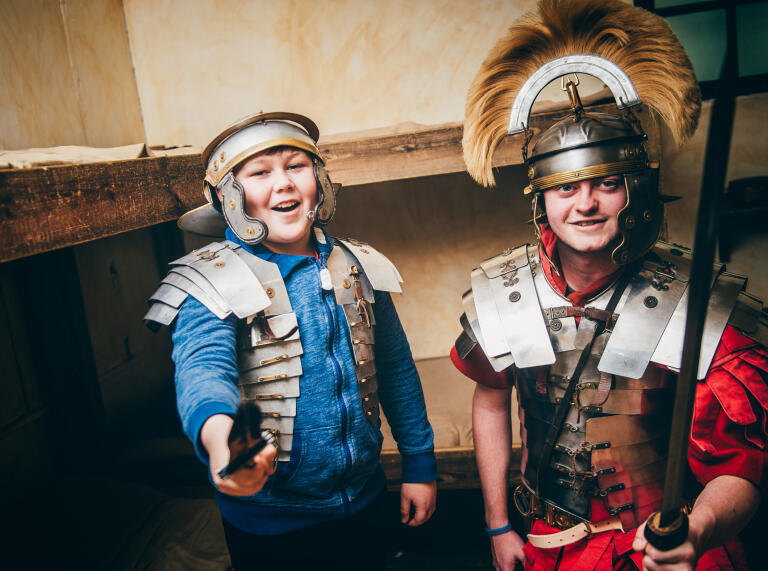 Two children dressing up in Roman armour.