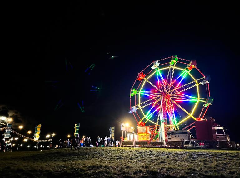 Ein Riesenrad, das bei Nacht in verschiedenen Farben leuchtet