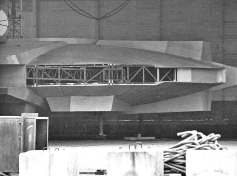 A black and white image of a film prop wooden spaceship under contruction.