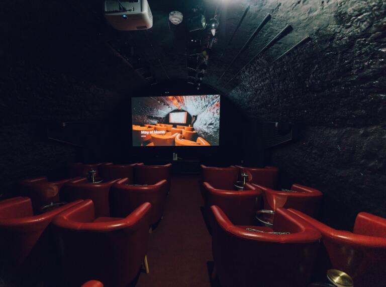 A small cinema room with red chairs.