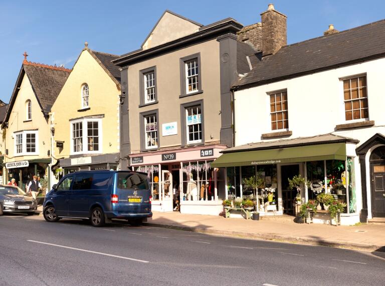 Cowbridge High Street shops and cars parked.