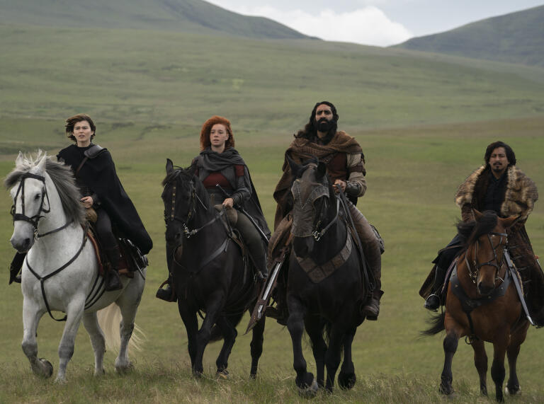 Kit (Ruby Cruz), Jade (Erin Kellyman), Boorman (Amar Chadha-Patel) and Graydon (Tony Revolori) on horseback with rolling green hills in the background, in Lucasfilm's Willow.