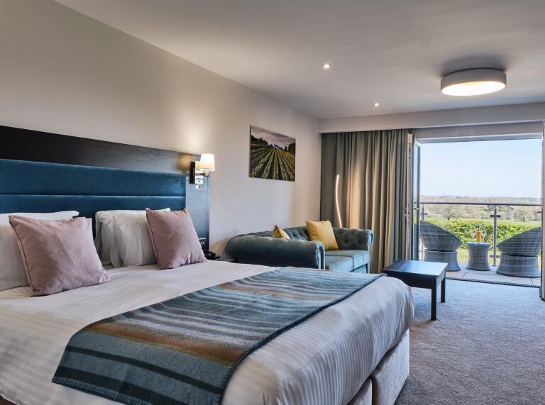 View of a superior room with a doible bed and sofa at Llanerch Vineyard.