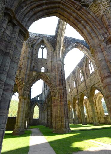 Inside a derelict abbey with magnificent arches and arched window frames.