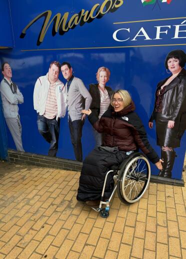 woman in wheelchair by large photo of Gavin & Stacey characters.