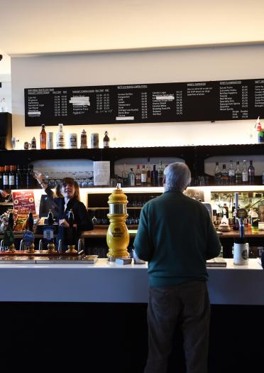 Man ordering at the bar in Chapter Arts Centre, Cardiff, with a woman serving him