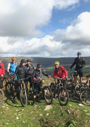 A large group of mountain bikers on a hilltop.