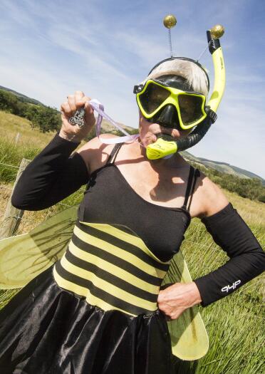 woman in bee outfit wearing snorkel and holding medal.