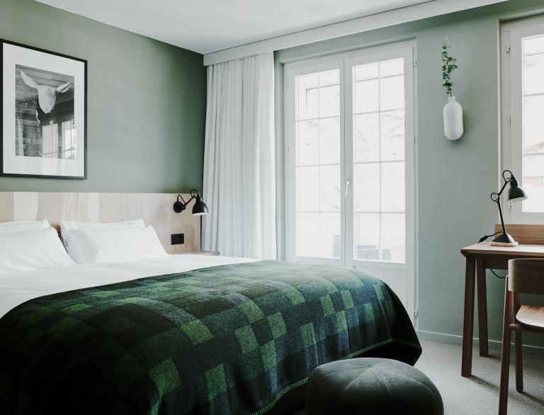 Bettdecke aus grüner Wolle von Melin Tregwynt auf einem Bett