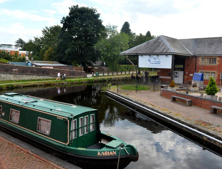 A museum building by a canal, with a green canal boat moored nearby.