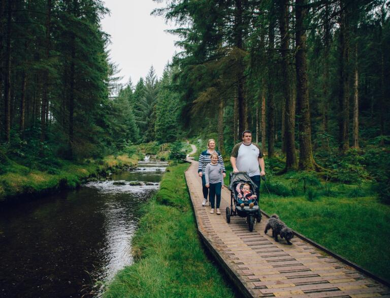 family with dogs on wooden platform alongside the river.