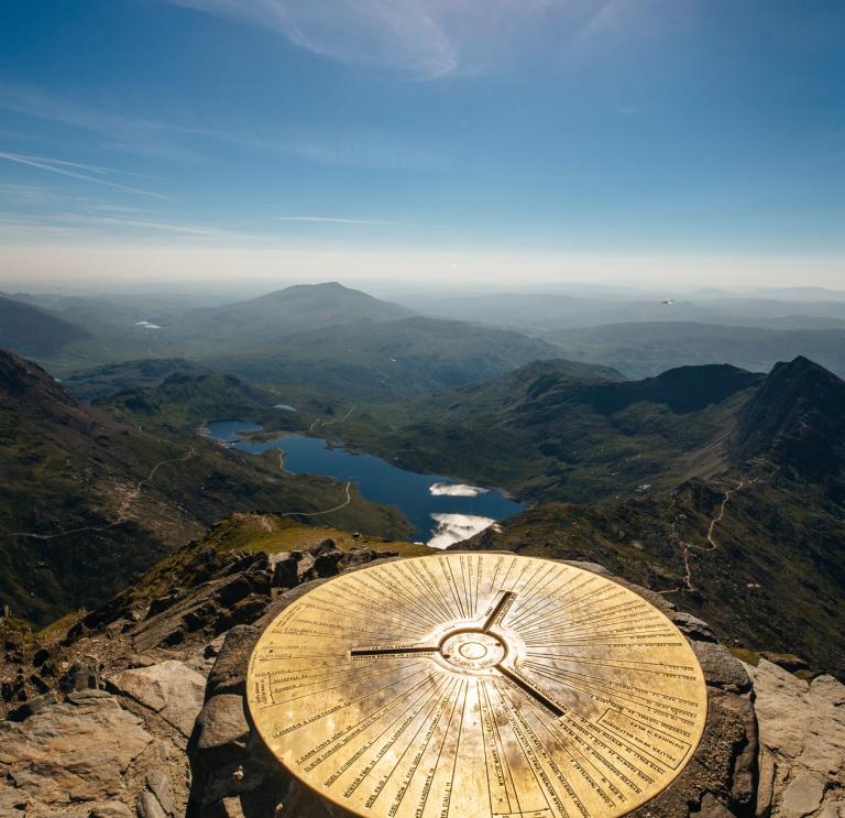 Trig point on top of Yr Wyddfa  (Snowdon) looking over the lakes.