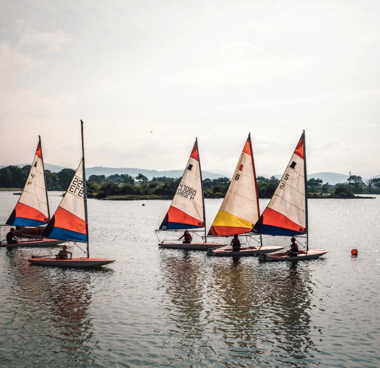 Five sailing boats on a lake.