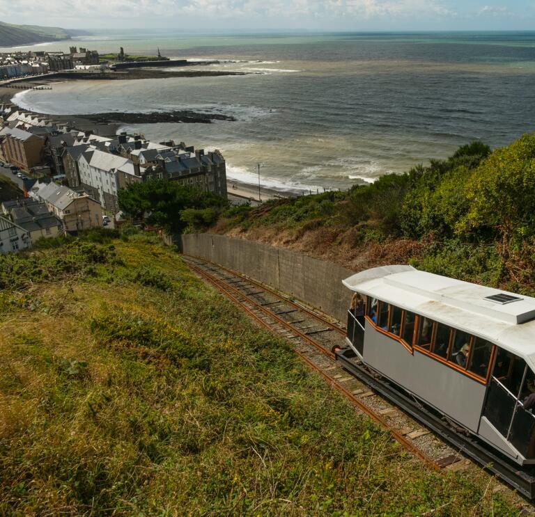 View from a hillside of a cliff railway and a seaside resort with a pier.