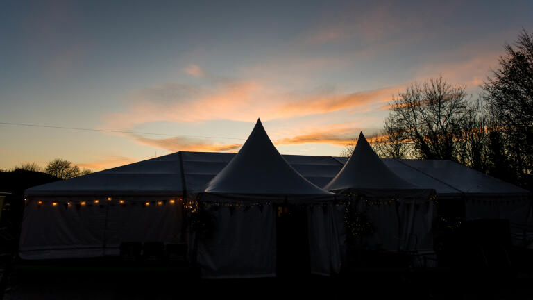 Ein Zelt mit Lichtern und einem Sonnenuntergang im Hintergrund.