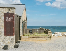 Beach House restaurant on the coast with a boat on the blue sea behind.