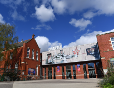 A red bricked old school building with a large hoarding over the entrance. 