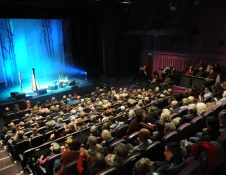 theatre audience with stage light up in background
