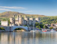 Looking across water to Conwy castle, with boats in the harbour.