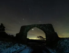 Dark skies, archway and trees.