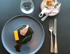 A plate with lamb, vegetables and gravy.