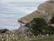 A stone built church at the edge of a cliff.
