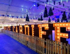 Cardiff sign lit up behind fence and Christmas trees hanging from ceiling.