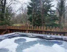 An outdoor hot tub with bubbling water overlooking a woodland view.