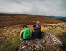 Walkers sat on a rock looking over green hills.