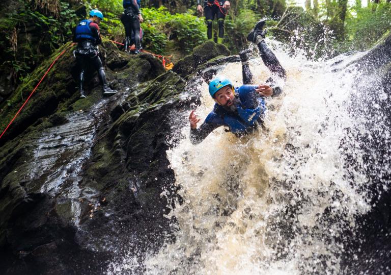 A man canyoning down rapids wearing safety gear.