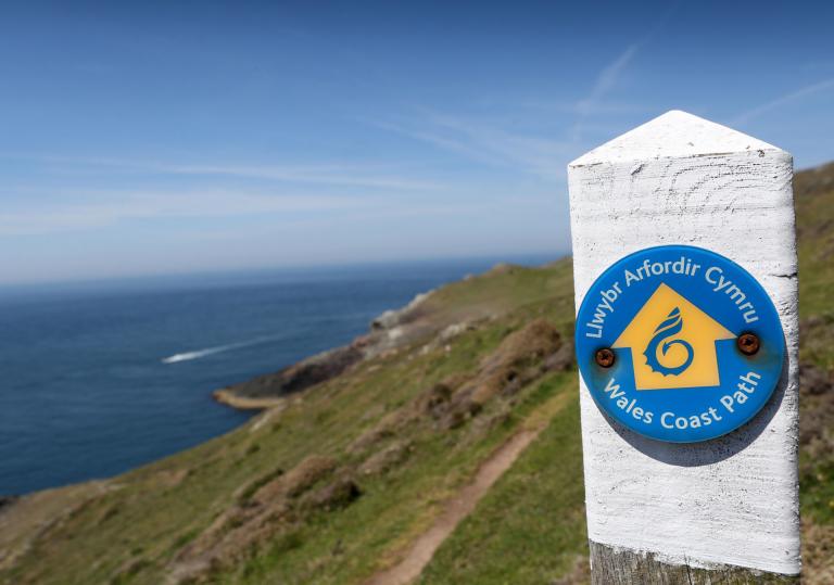 Signpost on coastal path looking over water.
