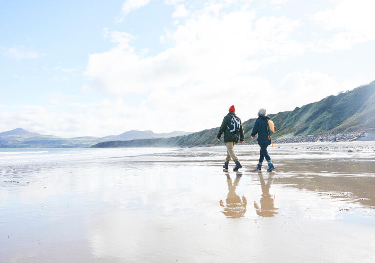 Couple walking on the beach at Porthdinllaen.
