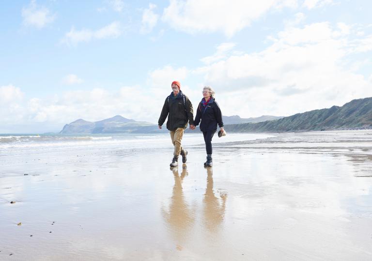 Couple walking on beach at Porthdinllaen.