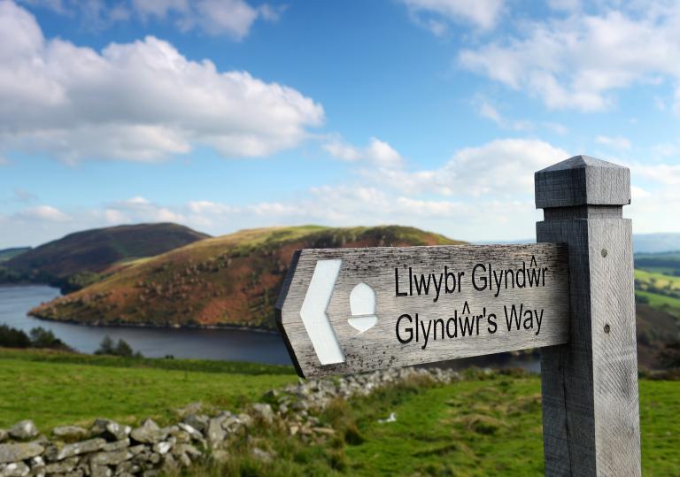 Signpost of Glyndŵr's Way with Clywedog Reservoir and hills in the background