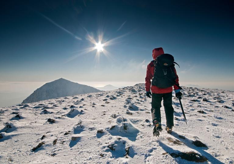 Walker / hiker / mountaineer approaching Snowdon summit in winter with heavy snow on ground