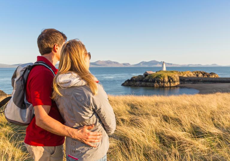 Couple looking out over beach and lighthouse.