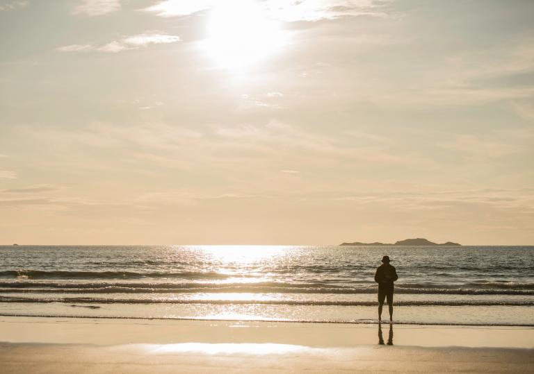 Man standing by sea at Whitesands Bay, Pembrokeshire, Westwales.