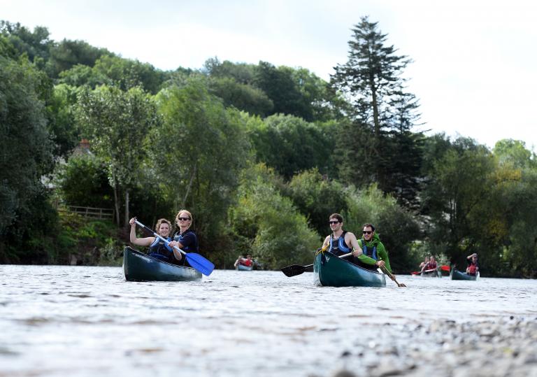 Image of a group of people canoeing open boats on the river Wye