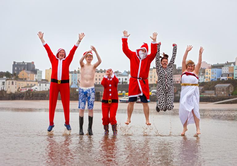 Swimmers jumping in Santa Claus / Father Christmas costumes.